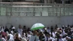 رجل أمن بالمسجد الحرام يحمي معتمراً من حرارة الشمس خلال خطبة أول جمعة برمضان